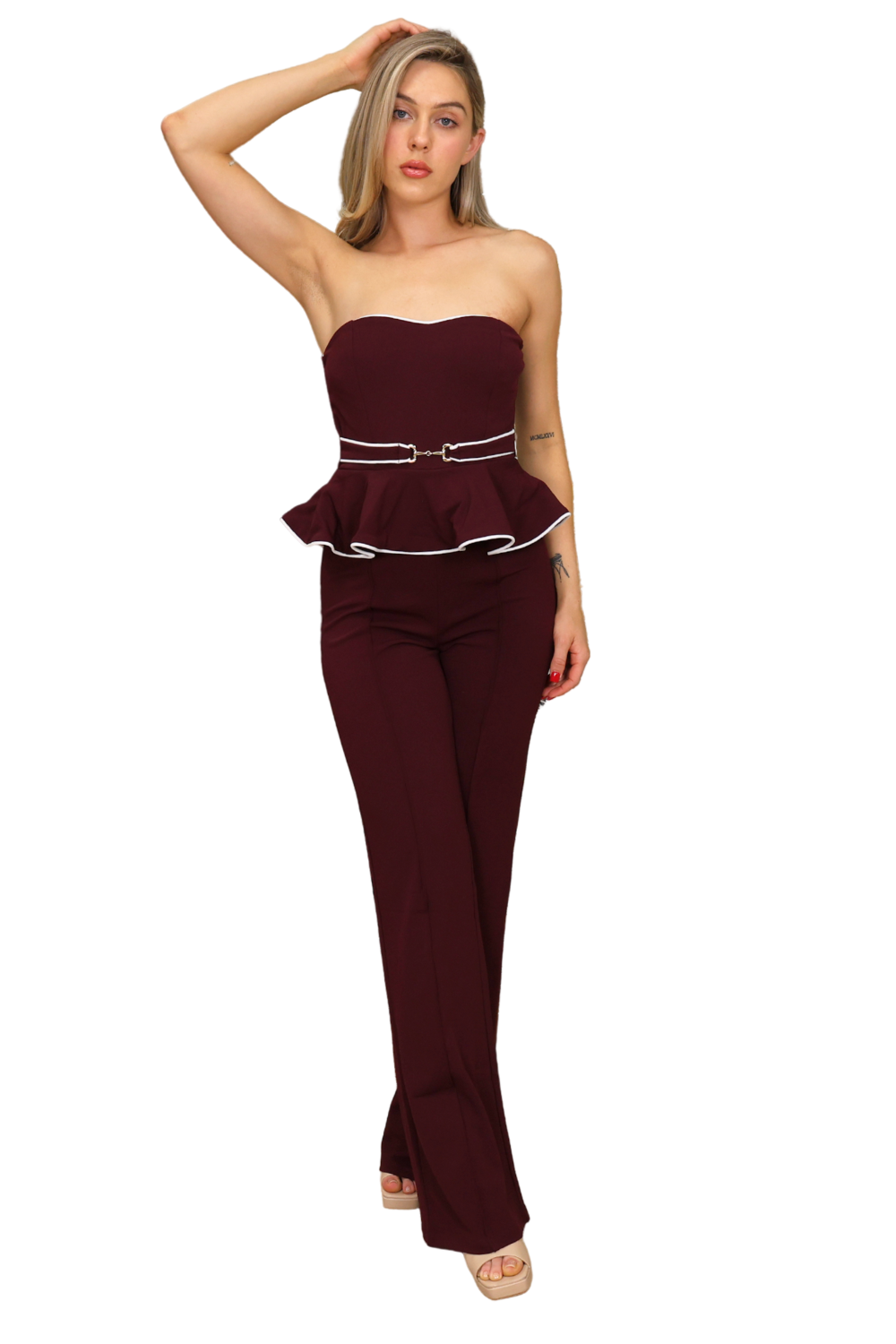 Woman wearing a burgundy strapless jumpsuit with a peplum top on a white background