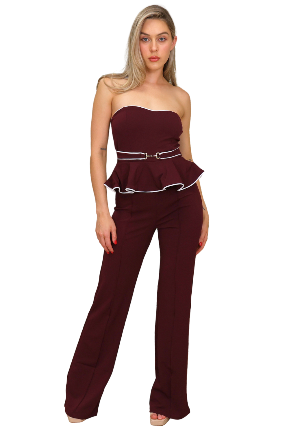 Woman wearing a burgundy strapless jumpsuit with a belt on a white background