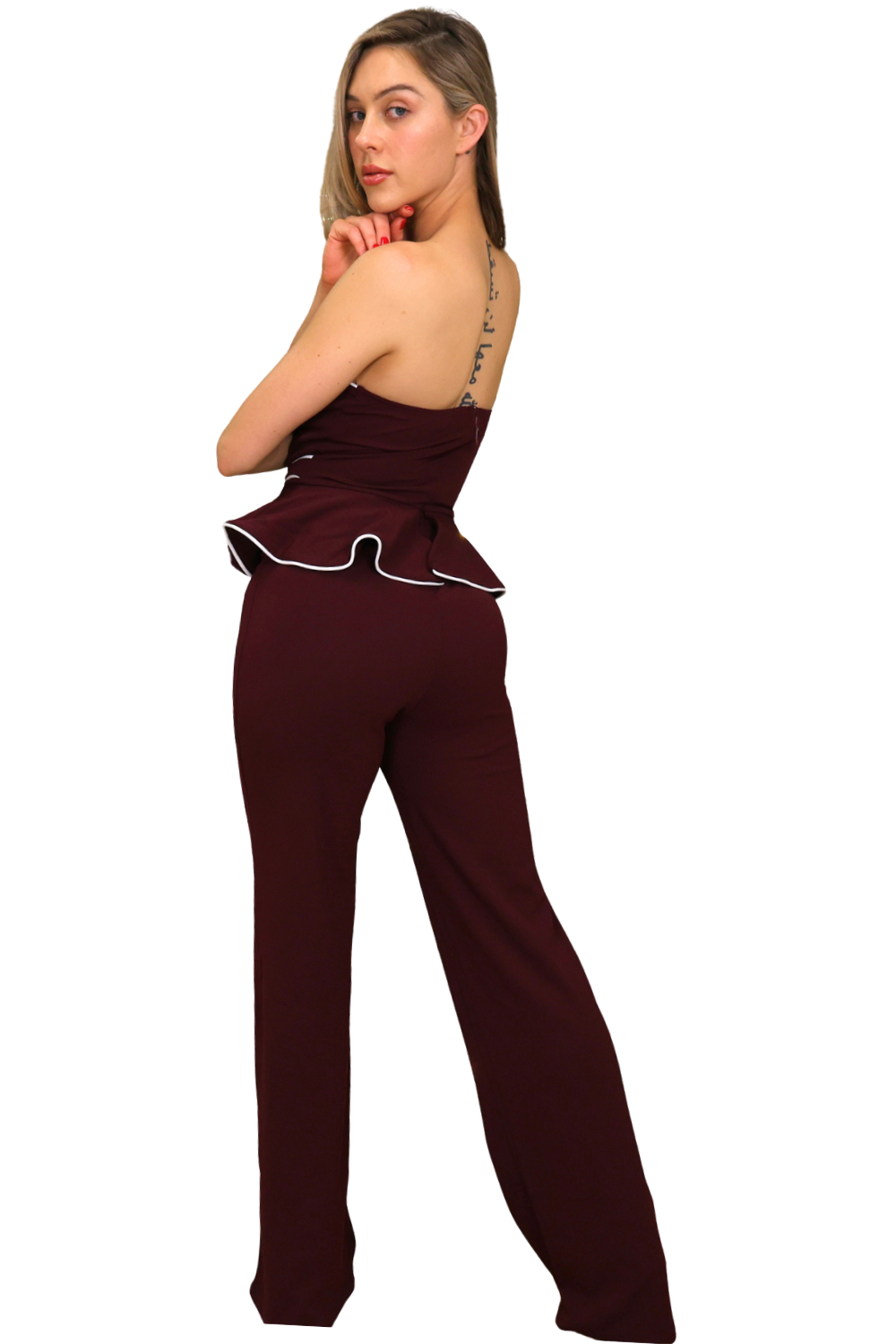 Woman wearing a burgundy jumpsuit with white piping on a white background