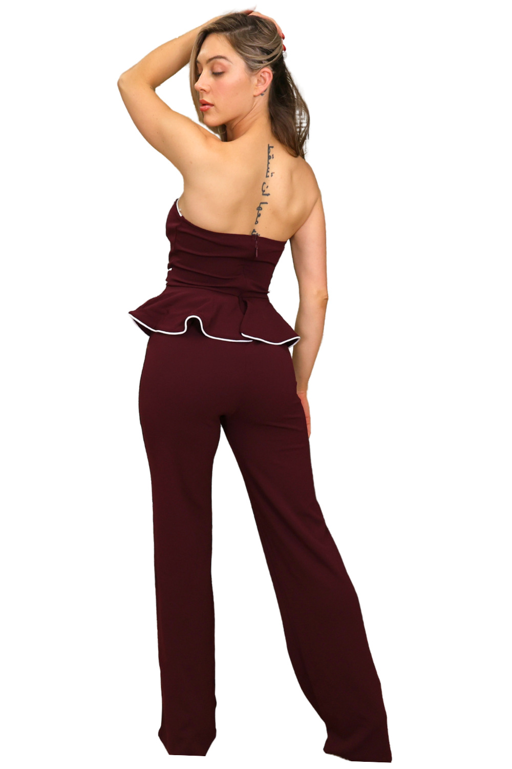 Woman wearing a burgundy jumpsuit with a white trim on a white background